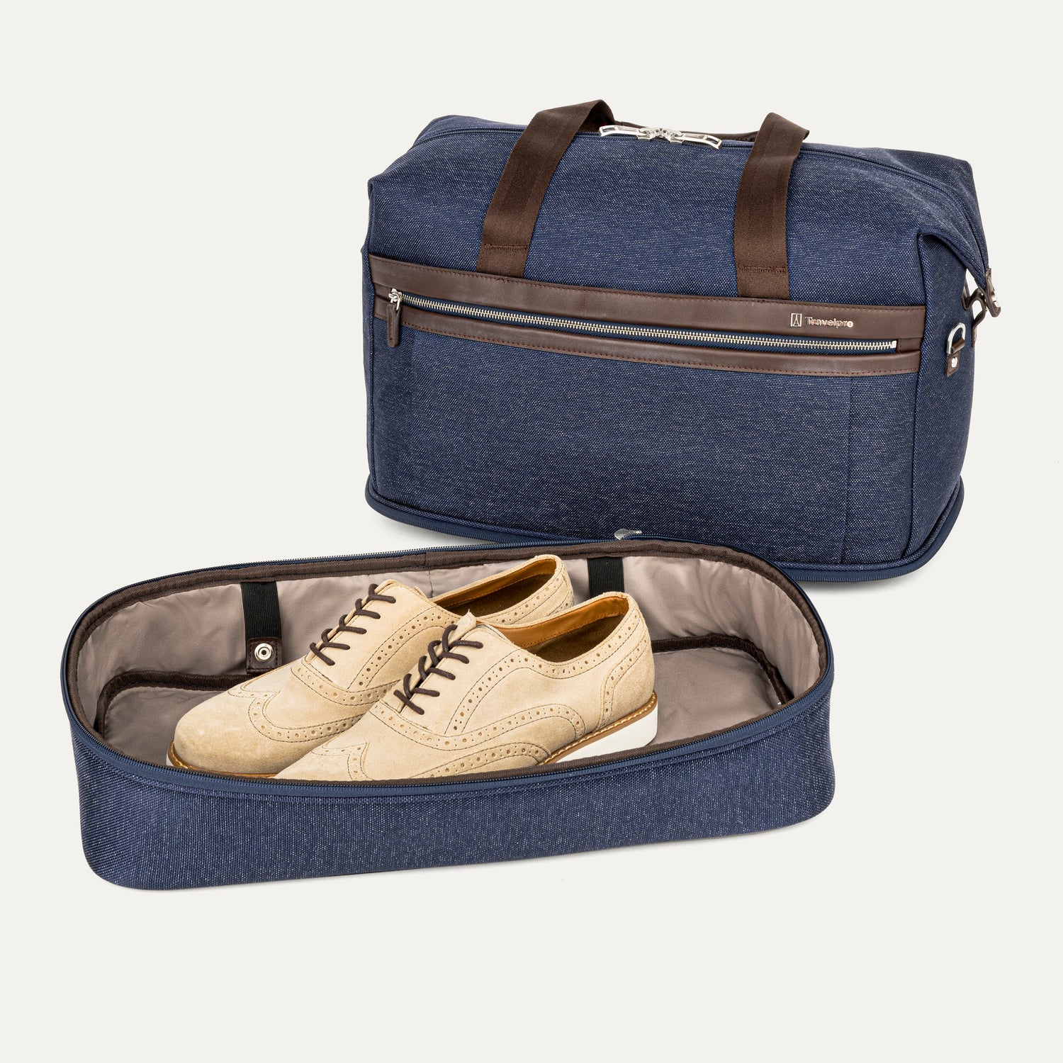Blue travel weekender with brown handles and a shoe compartment containing beige shoes on a white background