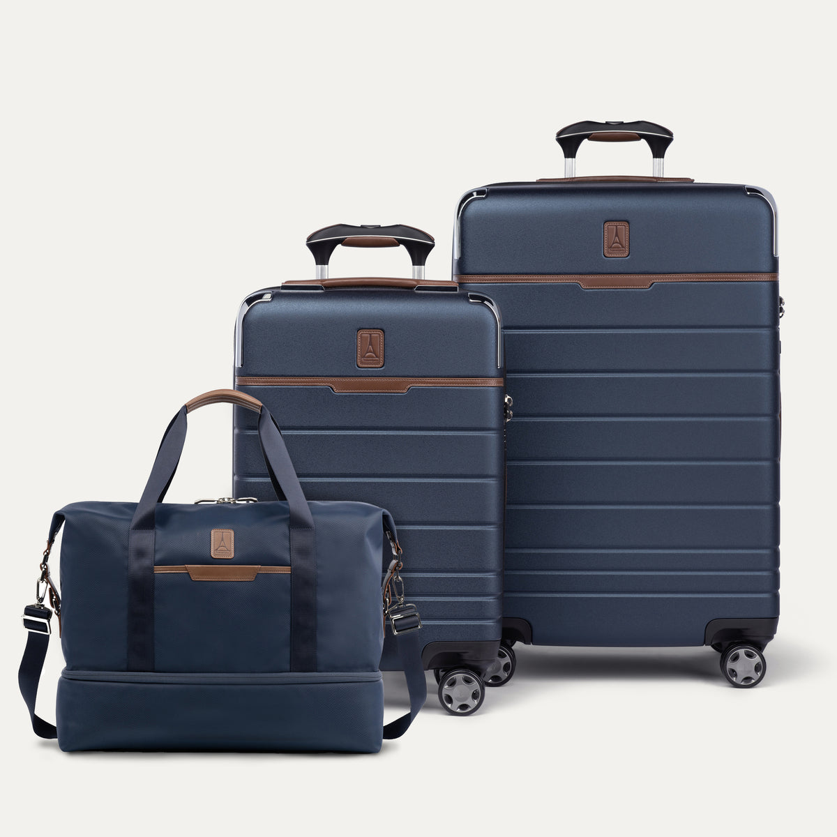 Two blue suitcases and a weekender with brown accents on a white background