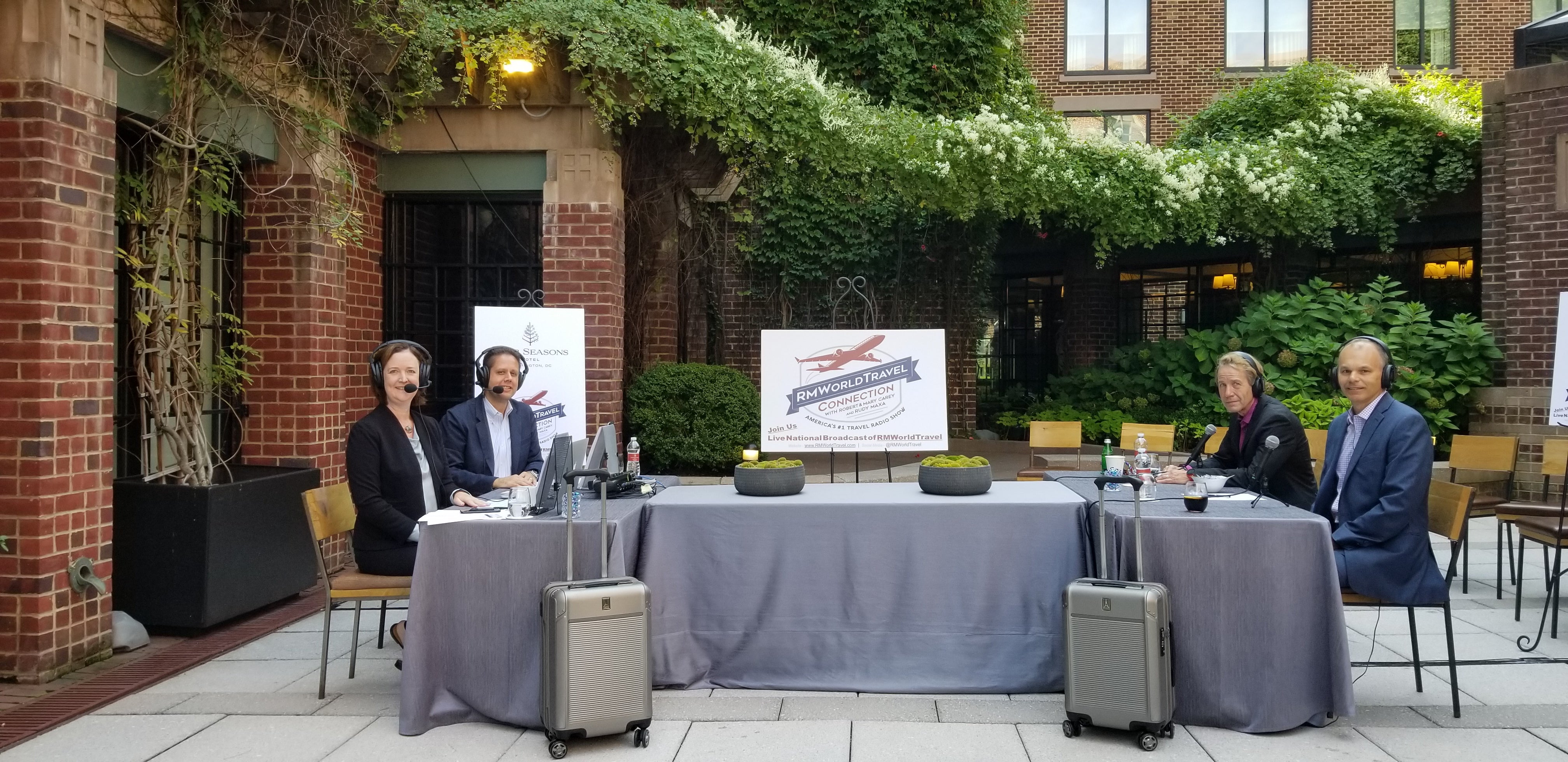 Radio show hosts Robert and Mary Cary hosting with two Travelpross platinum elite hardside suitcases being displayed