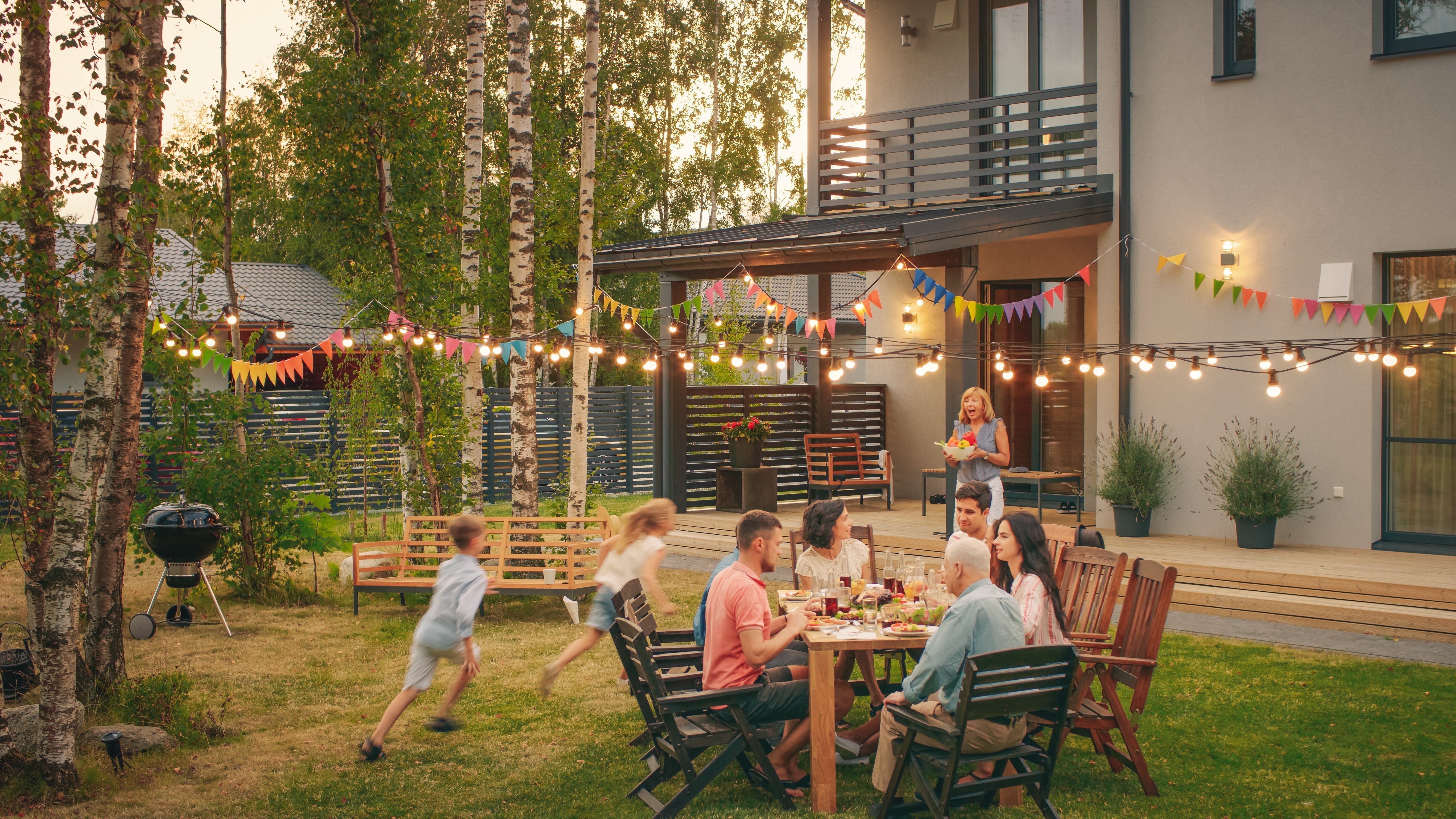 Family dining outdoors as kids play