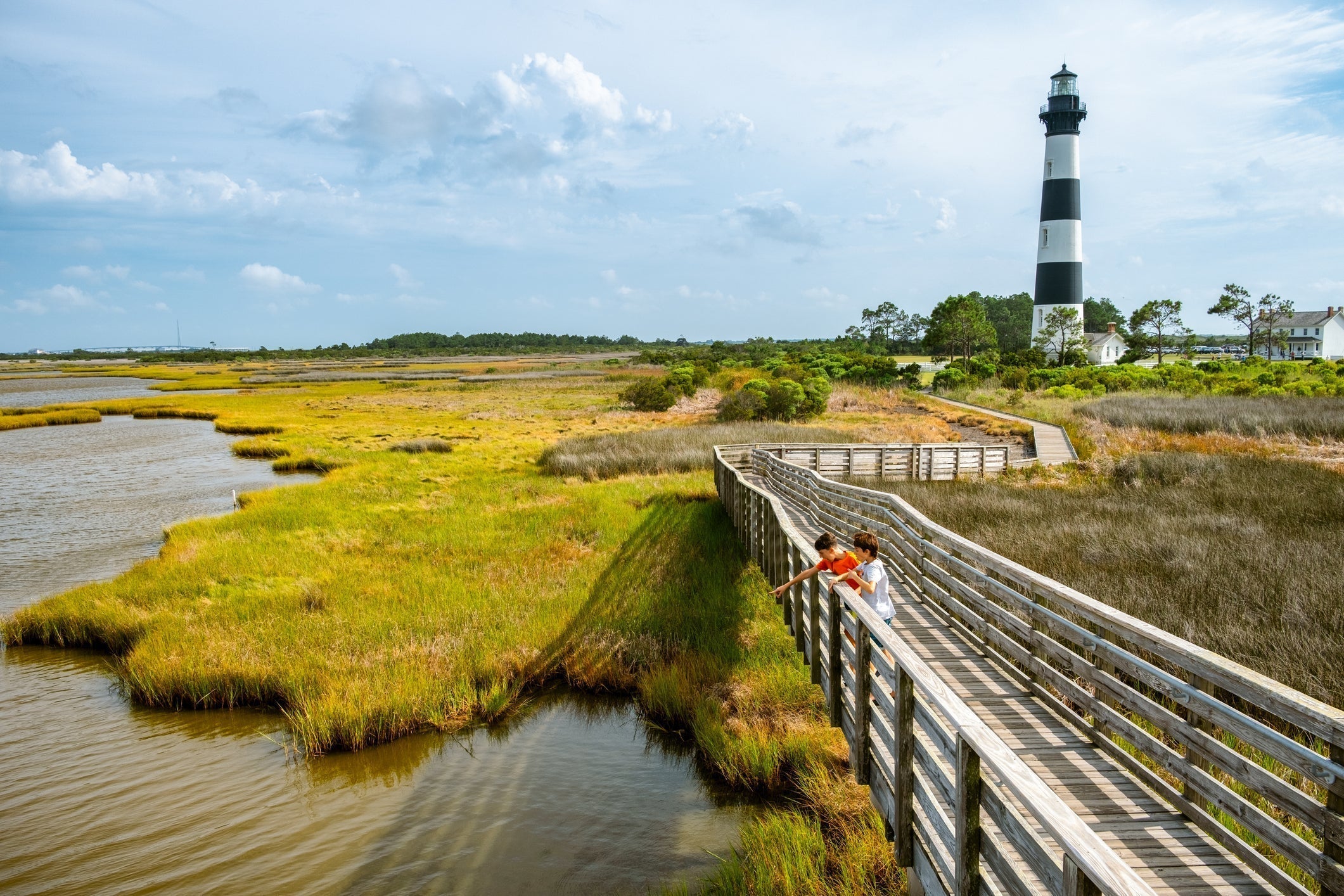 two children on a pier looking at marsh land