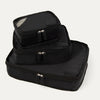A set of three black Travelpross packing cubes, with the largest at the bottom, medium in the middle, and the smallest at the top, all with zipper closures.