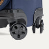 Close-up of a navy blue suitcase with black wheels on a white background