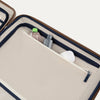 Open beige travel case with navy interior, containing toiletries on a white background
