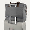 Grey weekender with a grey rear strap over suitcase handle on a white background