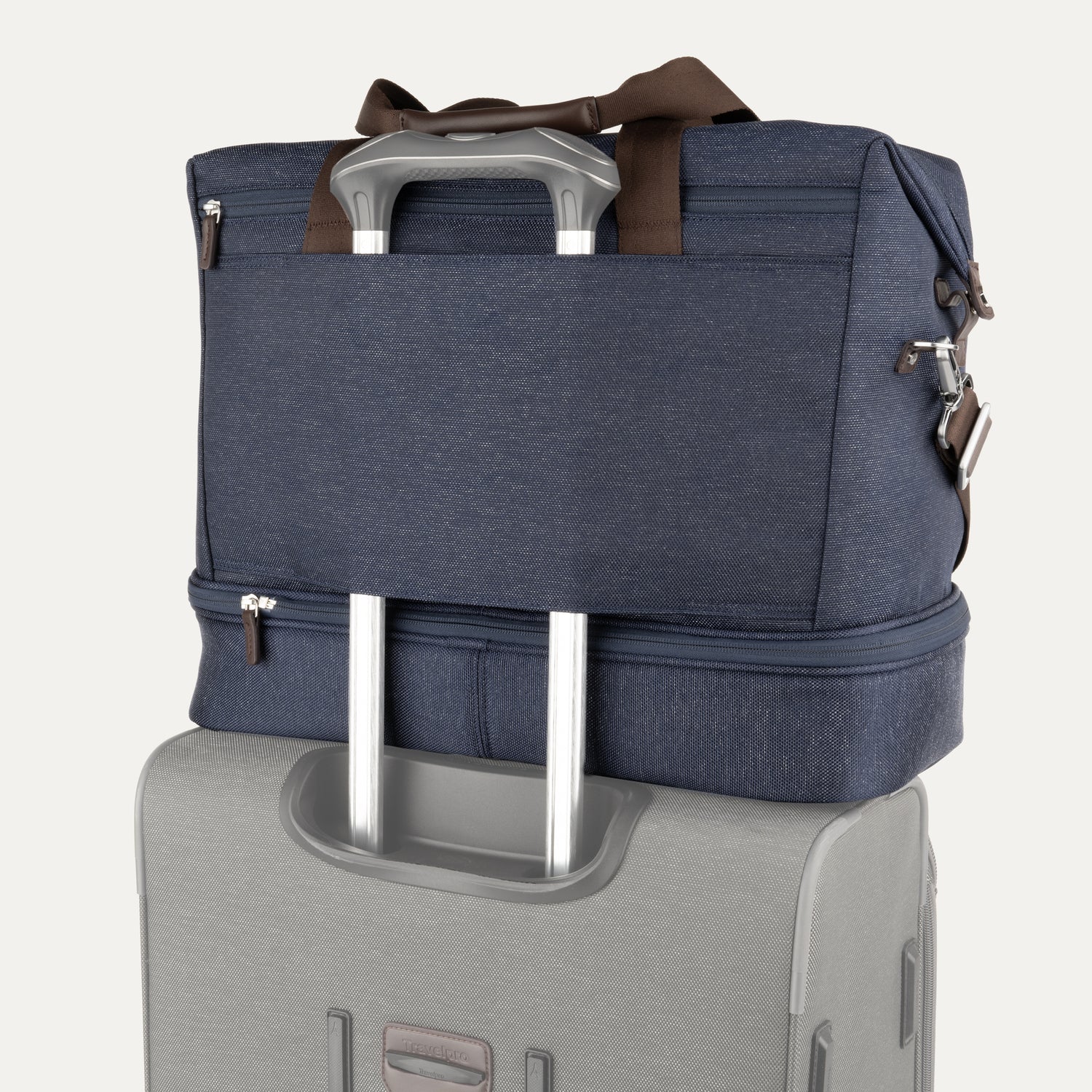True navy weekender with brown handles and a navy rear strap over suitcase handle on a white background
