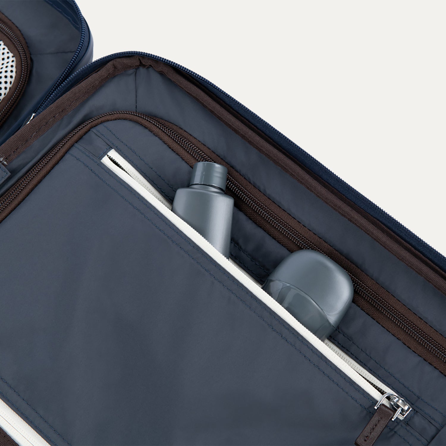 Interior view of Travelpross Platinum Elite Compact Carry-On Hardside Spinner in True Navy, showing zippered pocket with visible travel-size toiletries.

