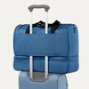 Blue weekender bag with rear strap on a white background