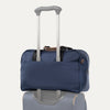 Blue tote bag stacked on top of luggage on a white background