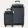 A set of two black hardside spinner suitcases, one carry-on and one check-in size, with textured finish, metallic corners, and wheels.