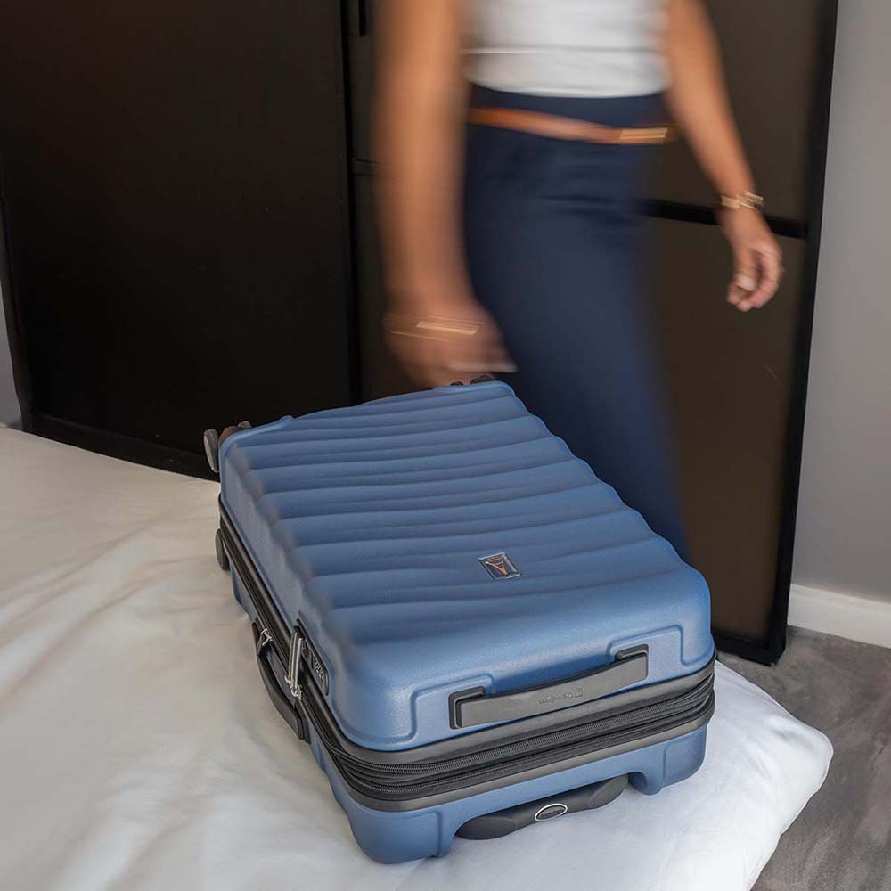 Blue suitcase on a bed with a person in the background