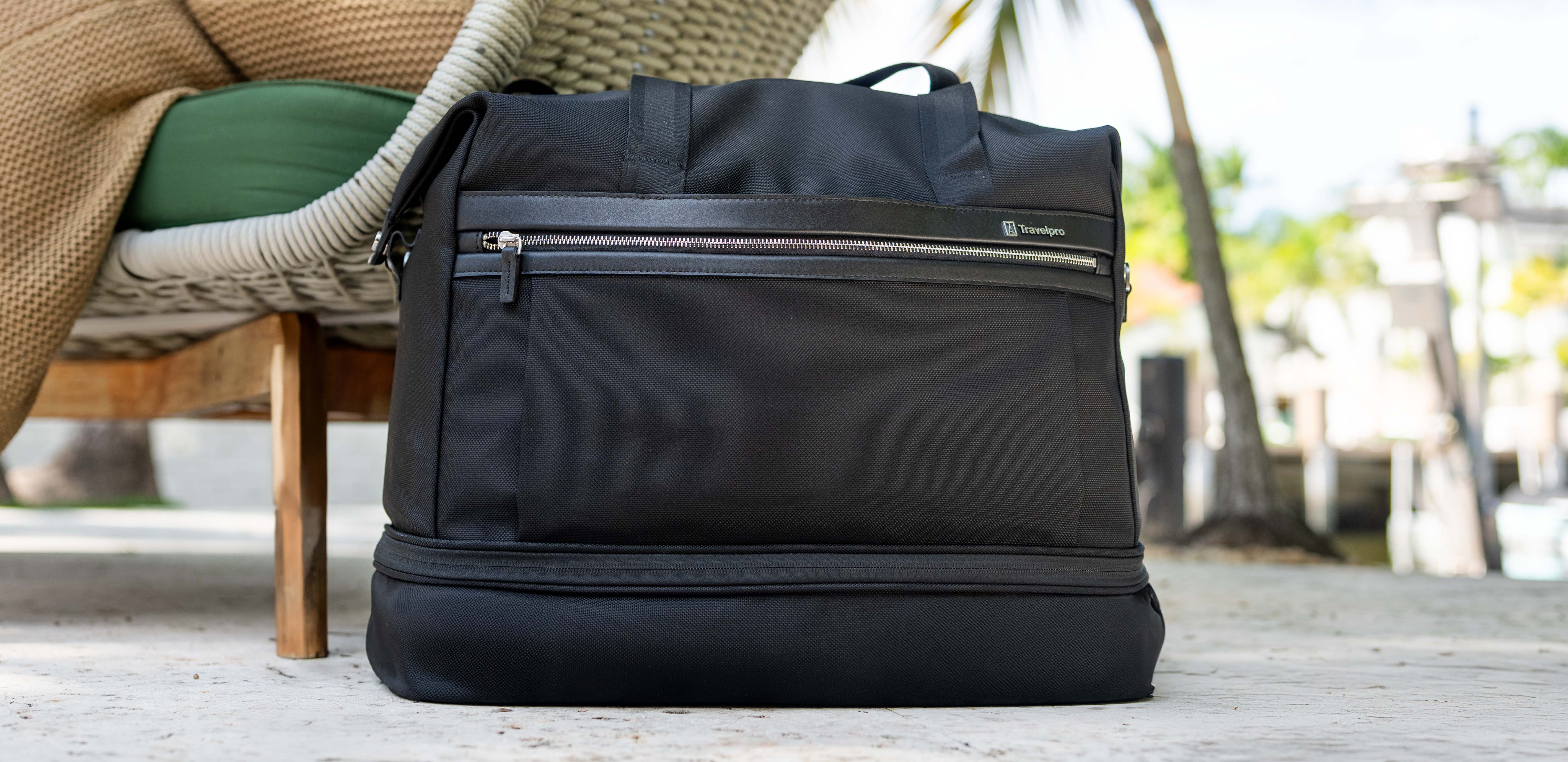Black travel bag on a wooden surface with blurred outdoor background