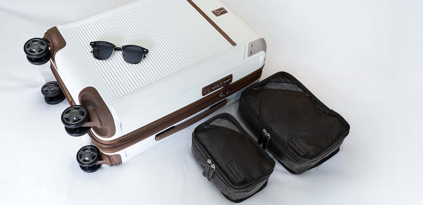 White suitcase with brown accents and sunglasses on a white background